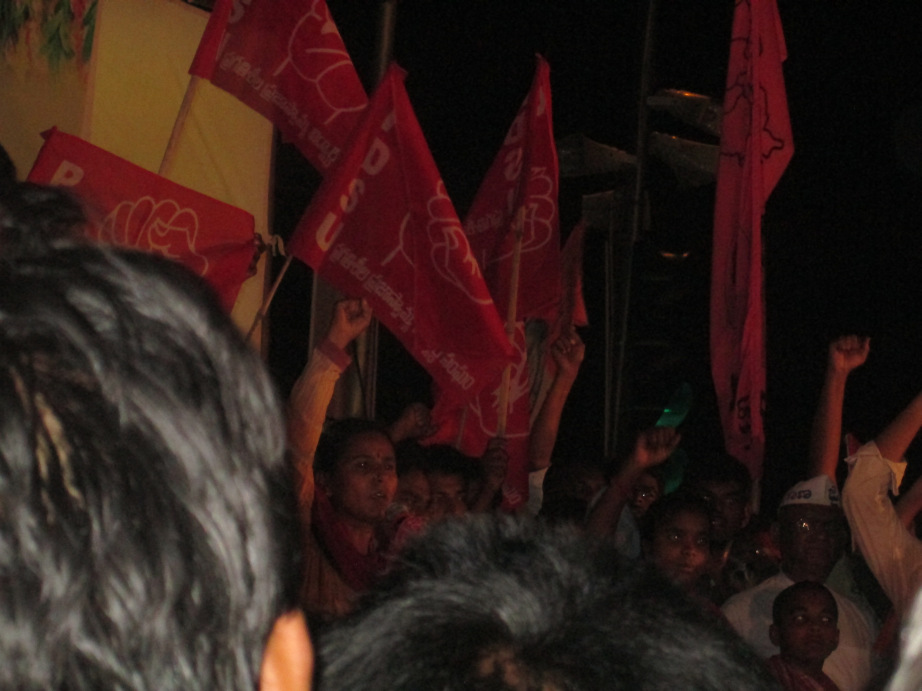 Students raising slogans with red flags at a night protest at Gun Park